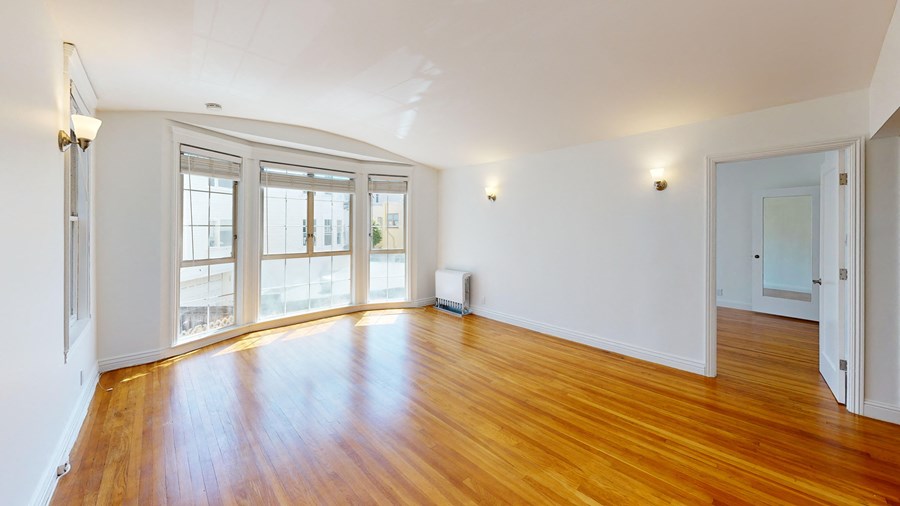 a living room with a hard wood floor and large windows